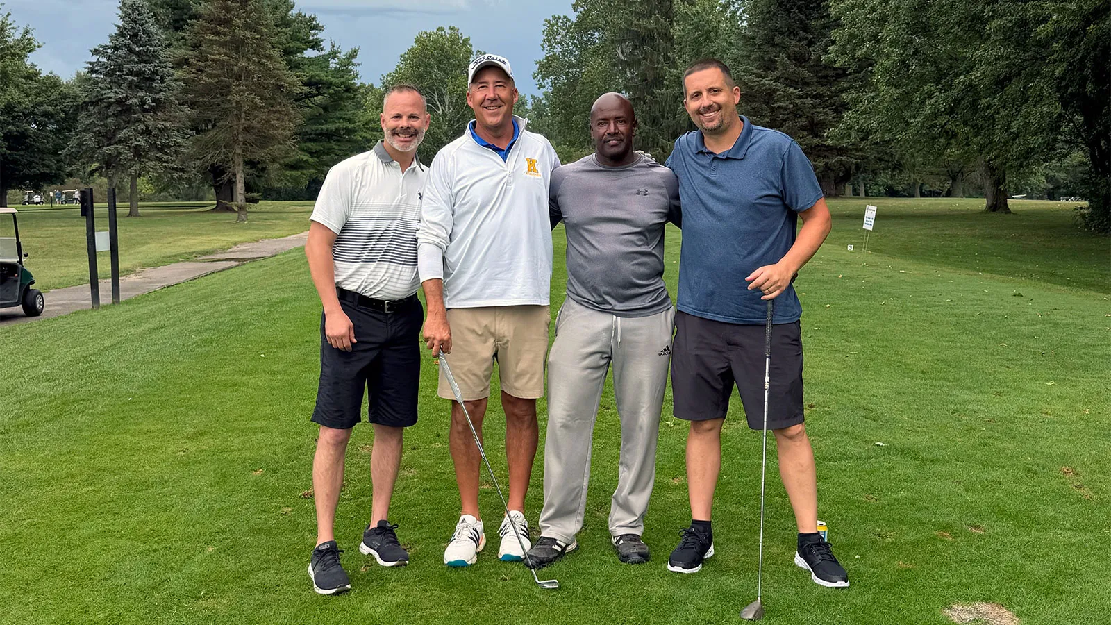 The winning foursome of the 3rd Annual T-Boo Classic — Derek, Andy, Ralph, and Rocky — standing arm in arm on the course, two of them holding clubs.